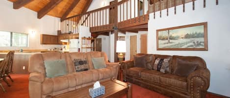 A spacious living room with two brown leather sofas, a wooden coffee table, and a painting on the wall.