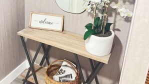 A wooden console table with a framed welcome sign, a potted orchid, and a wicker basket. - Amazing bohemian house with a pool in a very nice neighborhood  (Sunrise)