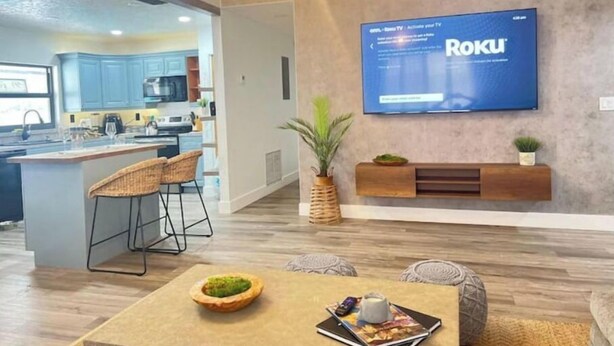 A modern living room with a flat-screen TV mounted on the wall, a wooden coffee table, and a seating area with chairs. - Amazing bohemian house with a pool in a very nice neighborhood  (Sunrise)