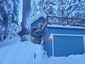 Ein zweistöckiges Gebäude mit Balkon und Garage, vor einer verschneiten Landschaft.