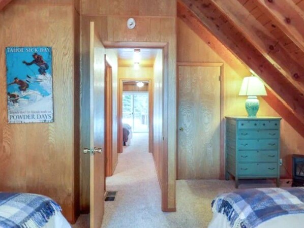 A narrow hallway leading to a bedroom with a bed and a dresser.