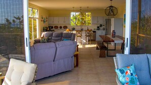 A spacious living area with a sofa, a dining table, and a kitchen in the background. - OCEANVIEWS AND SHORT WALK TO PLAYA NEGRA IN GATED COMMUNITY WITH SECURITY (Los Pargos)