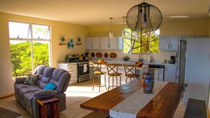 A modern kitchen with a dining area, a sofa, and a view of greenery outside. - OCEANVIEWS AND SHORT WALK TO PLAYA NEGRA IN GATED COMMUNITY WITH SECURITY (Los Pargos)