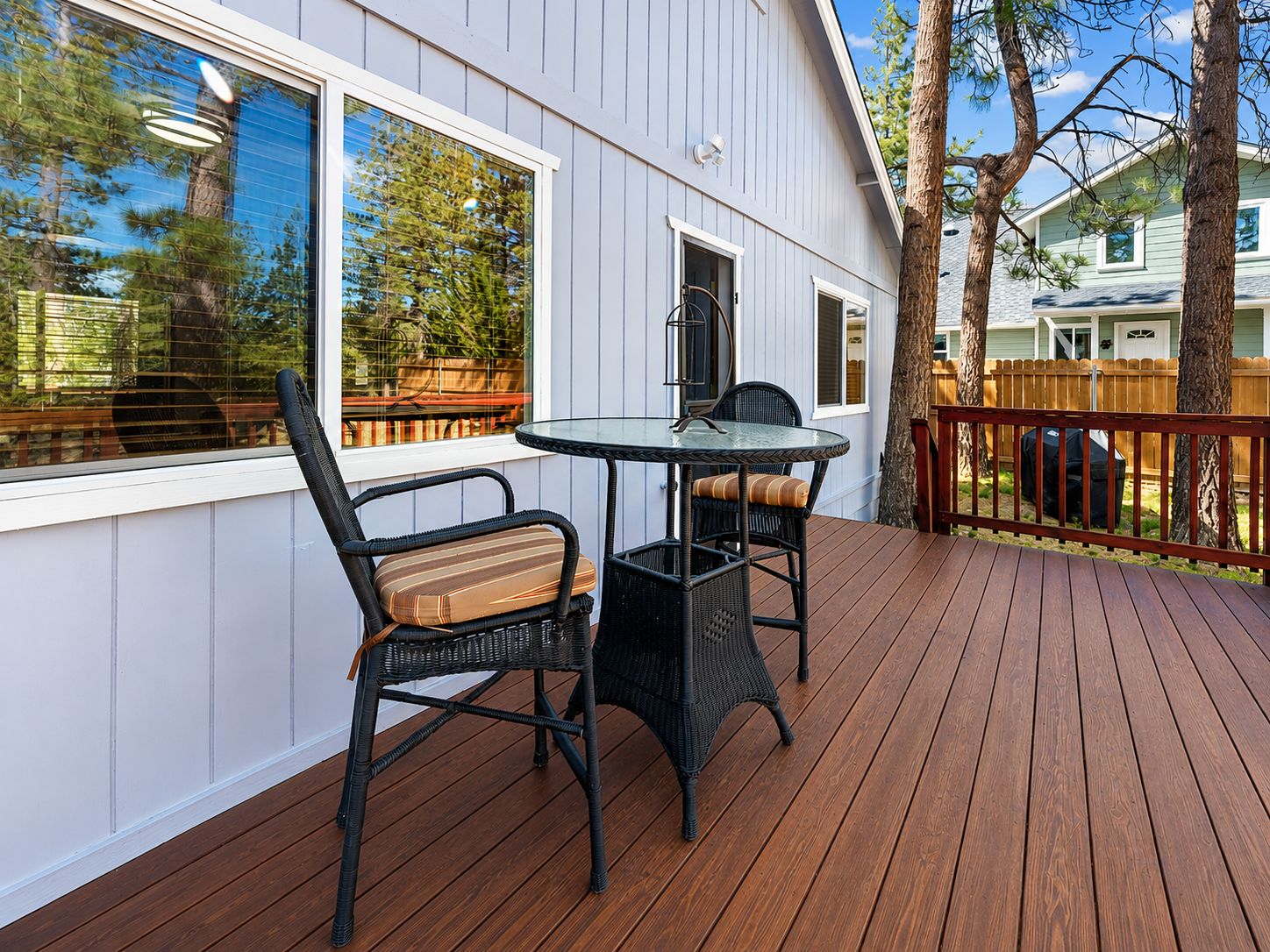 A deck with a table and chairs, a railing, and a view of the surrounding area.