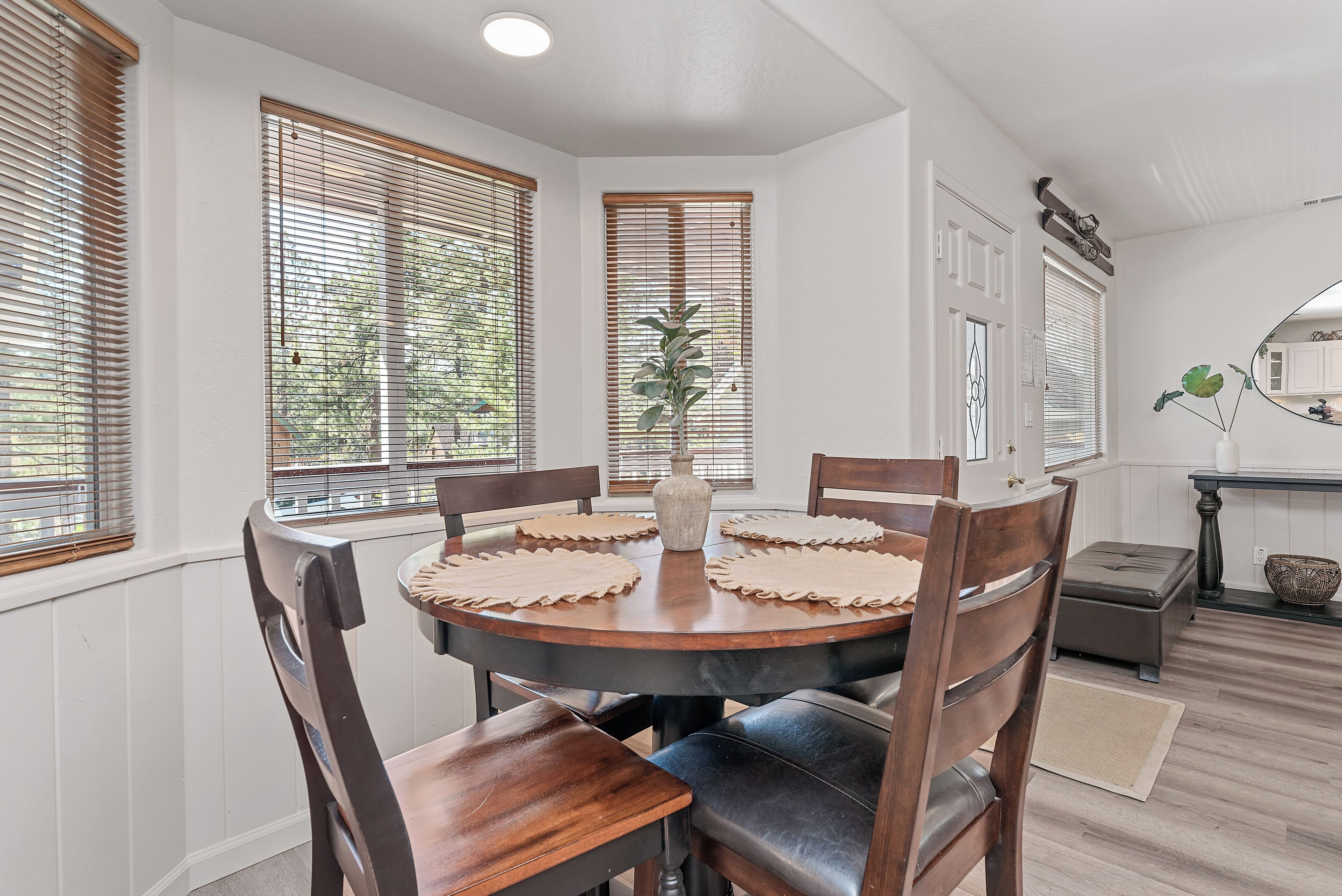 A dining area with a round wooden table, six chairs, and a vase of flowers.