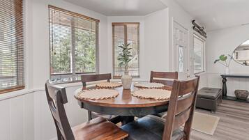 A dining area with a round wooden table, six chairs, and a vase of flowers.