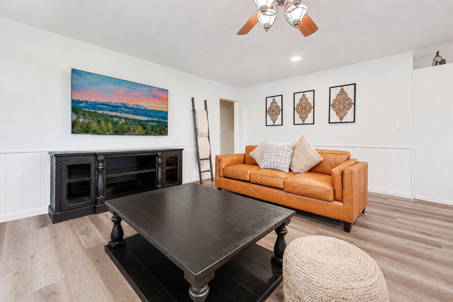 A living room with a fireplace, a leather sofa, a coffee table, and a painting on the wall.