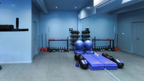 Ein Fitnessstudio mit blauen Wänden, unterschiedlicher Trainingsausstattung und einer Decken-Klimaanlage.