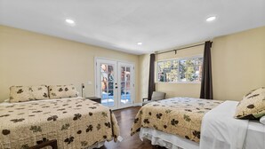 A hotel room with two beds, a window, and a door leading to a balcony. - Jaybird Lodge  (Big Bear Lake)