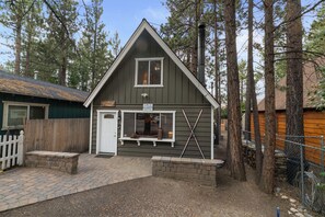 A cabin with a gabled roof, a front door, and a window.