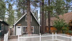A cozy cottage with a white picket fence, surrounded by tall pine trees. - Shady Pine Cottage (Big Bear City)