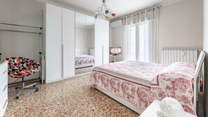 A bedroom with a bed, a chair, a television, and a radiator.