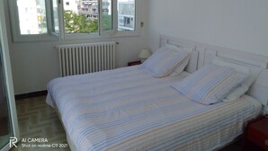 A bedroom with a bed, a window, and a radiator.