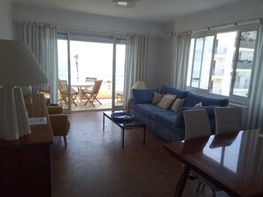 Ein Wohnzimmer mit einer Couch, einem Couchtisch, einem Fernseher und einem Essbereich mit Stühlen und einem Tisch.