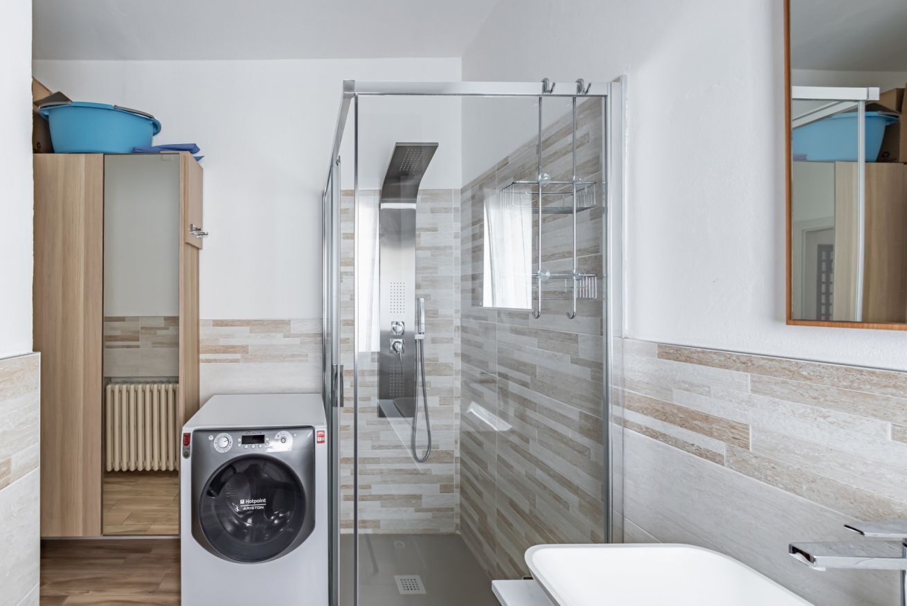 Ein kleines Badezimmer mit Duschkabine, Waschmaschine und Toilette.