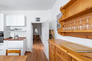 A kitchen with white cabinets, a wooden countertop, and a clock on the wall.
