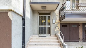 A building entrance with a set of stairs leading to a door with a metal gate.