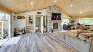 A spacious living area with a stone fireplace, wooden flooring, and a cozy couch. - Champion Vacation Rental with Fire Pit! (Champion)