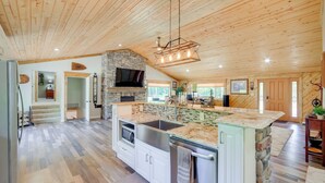 A spacious kitchen with a stone island, stainless steel appliances, and a large TV. - Champion Vacation Rental with Fire Pit! (Champion)