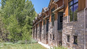 Un hilera de edificios de piedra y madera con balcones, ubicados en una zona boscosa.