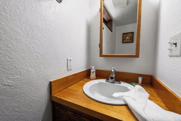 A bathroom with a wooden vanity, a white sink, a mirror, and a towel hanging on the wall.