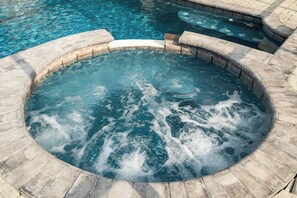 A hot tub with a stone border, surrounded by a pool. - Budget Friendly/ Pool/Spa/ Game Room/ Gated Community (Davenport)