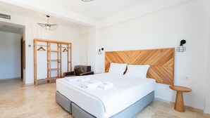 Un dormitorio ordenado con una cama grande, un cabecero de madera, un armario colgado y una mesita redonda.