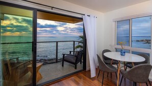 Varanda com vista para o mar, uma mesa com cadeiras e uma janela com vista para o mar.
