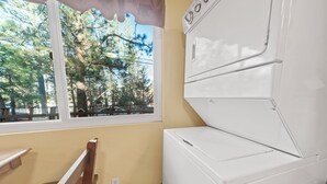 A laundry room with a large window, a wooden bench, and a white washer and dryer. - Irie's Retreat (Sugarloaf)