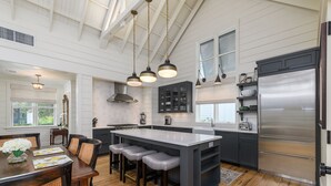 Una cocina moderna con una isla grande, muebles oscuros y electrodomésticos de acero inoxidable.