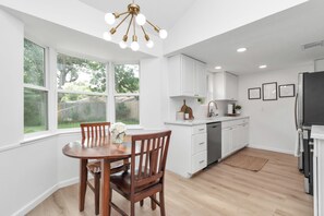 A modern kitchen with white cabinets, a built-in oven, and a stainless steel refrigerator.