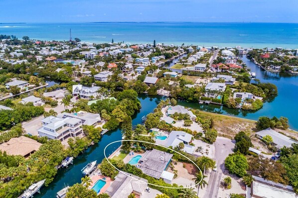 An aerial view of a coastal residential area with houses, a marina, and a swimming pool. - Canal Place: Boat Dock, Pool & Spa, On Canal by Anna Maria Life Vacation Rentals (Anna Maria)