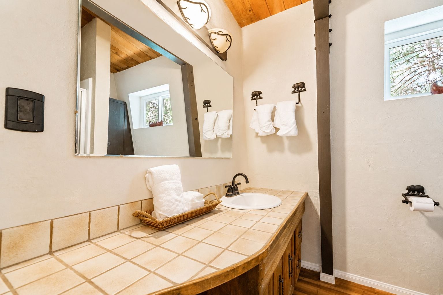 A bathroom with a wooden vanity, a large mirror, and two wall-mounted towel racks.