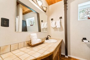 A bathroom with a wooden vanity, a large mirror, and two wall-mounted towel racks. - Sherwood Pines (Big Bear City)