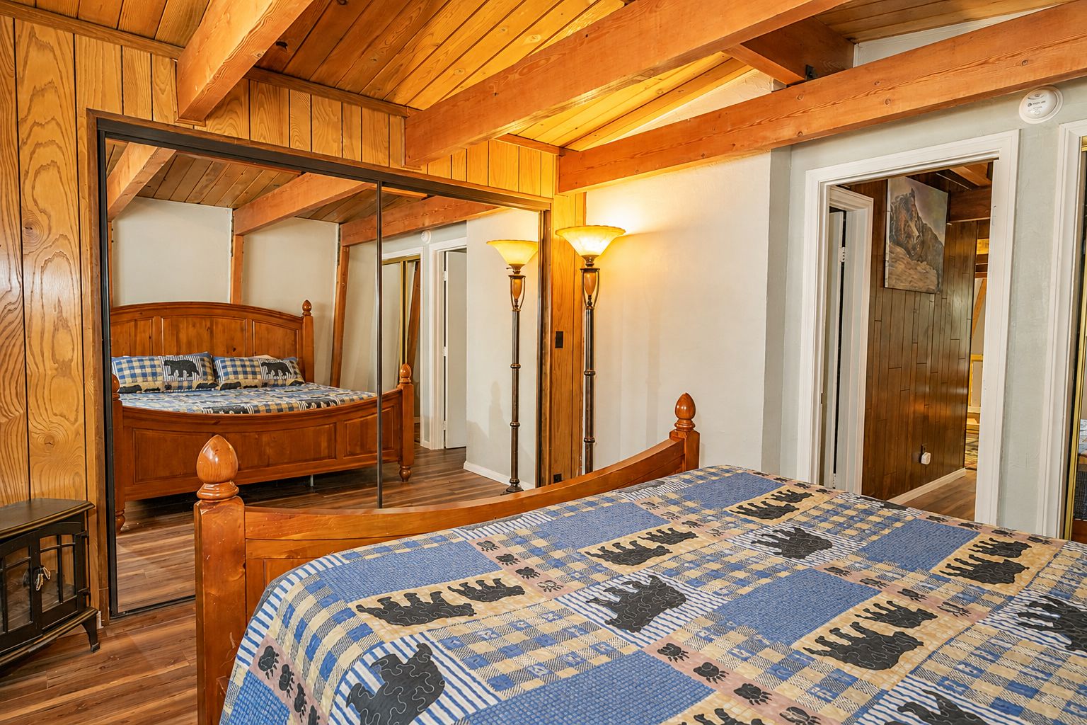 A bedroom with a wooden bed, a large mirror, and a floor lamp.