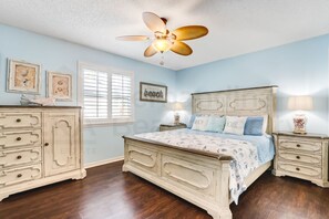 A bedroom with a bed, dresser, nightstands, and a ceiling fan.