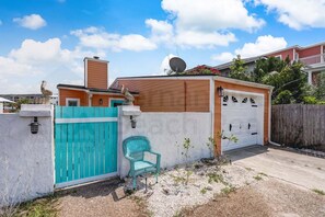 A residential property with a garage, a turquoise gate, and a small garden area.