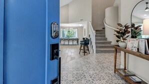 A modern hotel lobby with a blue door, a staircase, a dining area, and a reception desk. - Paradise Villa - Spacious Home with Private Pool, Office, and Pool Table in Scottsdale (Scottsdale)