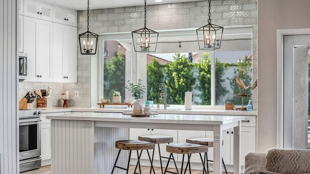 A modern kitchen with white cabinetry, a large island with stools, pendant lighting, and a view of greenery outside. - Paradise Villa - Spacious Home with Private Pool, Office, and Pool Table in Scottsdale (Scottsdale)