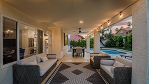 A covered outdoor area with a pool, seating, and a kitchen visible through an open door. - Paradise Villa - Spacious Home with Private Pool, Office, and Pool Table in Scottsdale (Scottsdale)