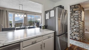 Une cuisine moderne dotée d’un grand îlot central, d’appareils électroménagers en acier inoxydable et d’un mur décoratif en pierre.