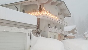 A multi-story building with snow-covered balconies and a garage door. - Ferienwohnung - Wald am Arlb. (Wald am Arlberg)