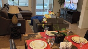 A dining area with a table set for four, a sofa, a TV, and a ceiling fan. - Chandler retreat, golfers home away from home. STR license309317
tpt21606535 (Chandler)