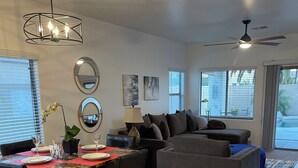 A modern living room with a dining area, grey sofa, and a ceiling fan. - Chandler retreat, golfers home away from home. STR license309317
tpt21606535 (Chandler)