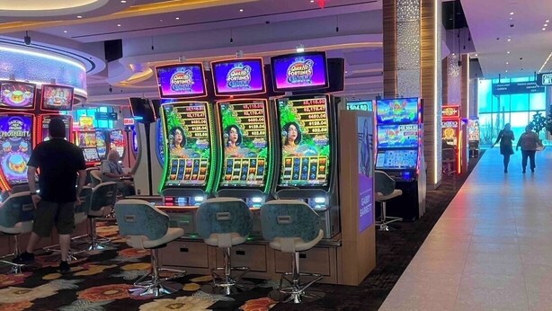 A casino floor with slot machines, bar seating, and a carpeted walkway. - Chandler retreat, golfers home away from home. STR license309317
tpt21606535 (Chandler)