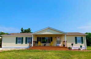 A single-story house with a front porch, two chairs, and a small garden area. - Charming Home with Country Views (Grafton)