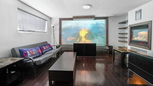 A modern living room with a large TV, a sofa with a Canada-themed pillow, a wooden coffee table, and a fireplace. - Stylish 1 bedroom basement unit with renovated bathroom & in-suit Jacuzzi. (Richmond Hill)
