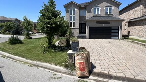 A two-story house with a garage, surrounded by a well-maintained lawn and a driveway. - Stylish 1 bedroom basement unit with renovated bathroom & in-suit Jacuzzi. (Richmond Hill)