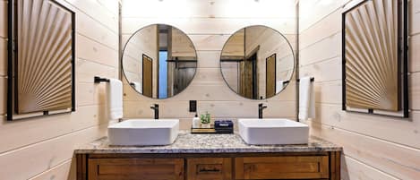 Une salle de bain avec des lambris en bois, deux lavabos, un meuble-lavabo avec des tiroirs et de grands miroirs.
