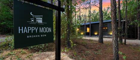 Une enseigne indiquant « Happy Moon Broken Bow », avec une cabane en arrière-plan.